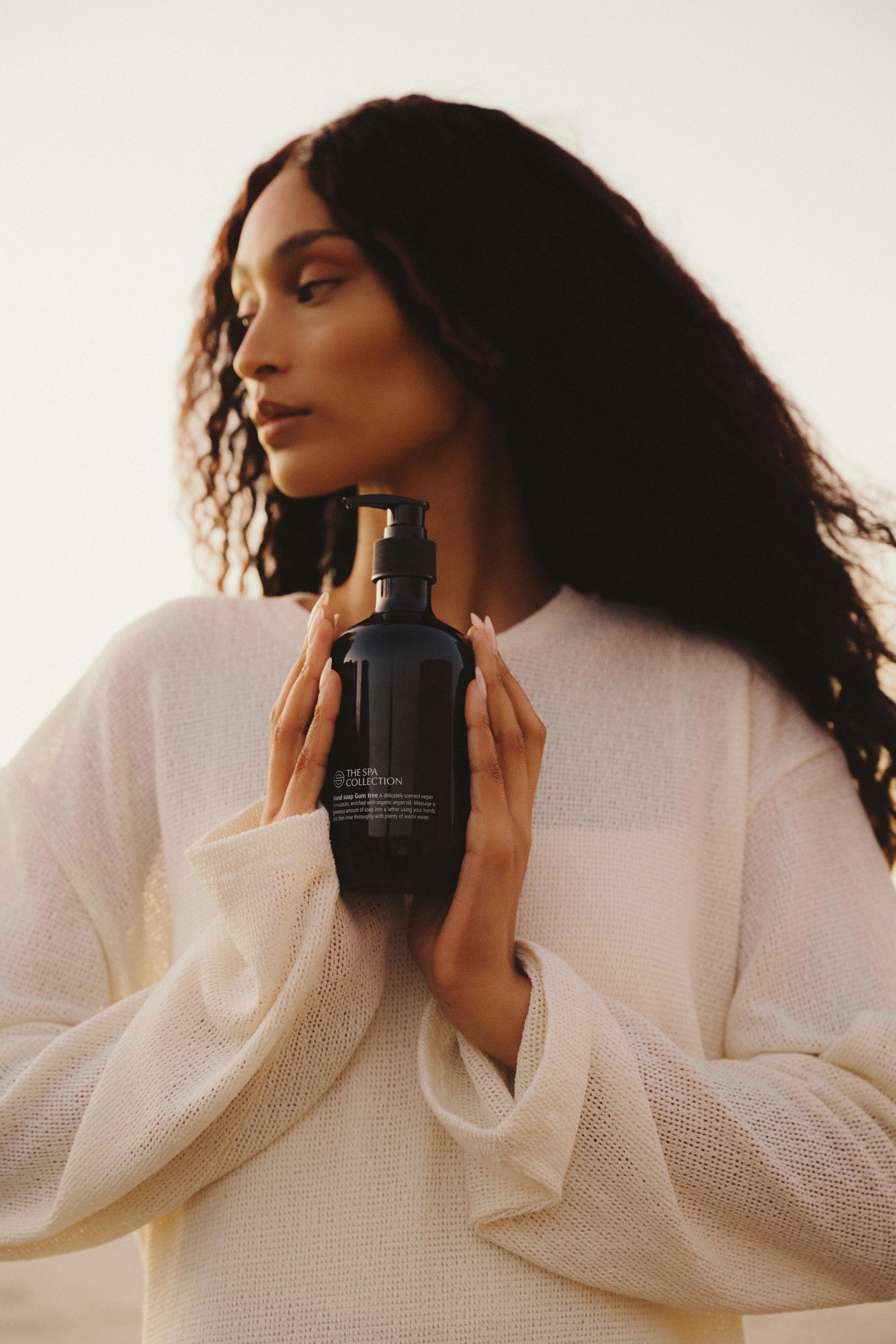 Close-up of The Spa Collection Gum Tree hand soap bottle held in hand under soft lighting